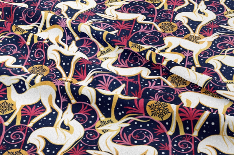 May include: A navy blue fabric with a repeating pattern of white stylized deer, pink and yellow stylized palm trees, and gold stylized snowflakes. The background is a dark blue with white dots.