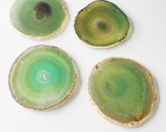 May include: Four green agate coasters with gold trim. The coasters are round and have a natural, organic look.