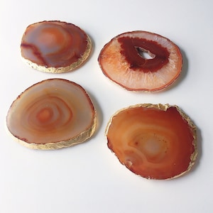 May include: Four agate coasters with gold trim. The coasters are round and have a natural, organic look. They are perfect for adding a touch of elegance to any home.