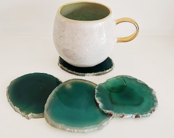 May include: Set of four green agate coasters with a white ceramic mug with a gold rim and handle on top of one of the coasters.