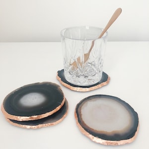 May include: Four agate coasters with a copper trim. The coasters are in two different color combinations: black and white, and black and white with a copper trim.