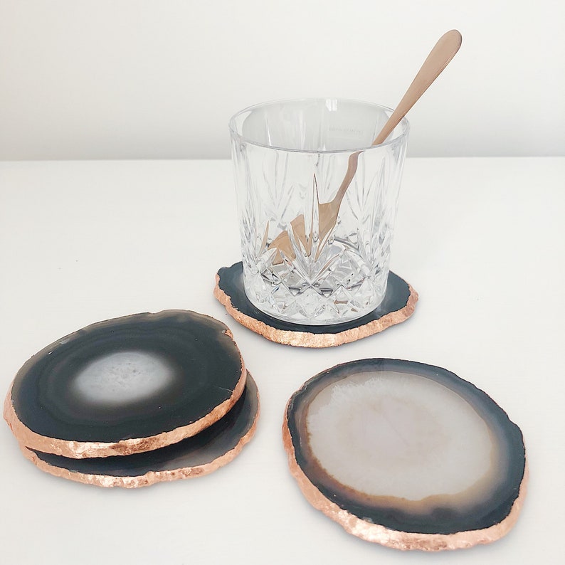 May include: Four agate coasters with a copper trim. The coasters are in two different color combinations: black and white, and black and white with a copper trim.