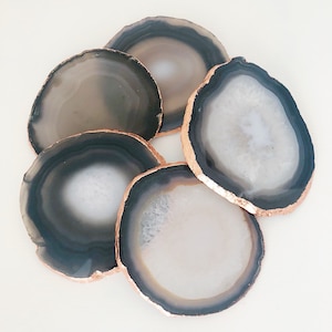 May include: Set of six agate coasters with a copper-toned edge. The coasters are round and have a natural, organic look.