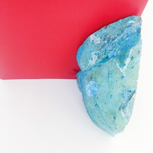 May include: A blue and white textured rock with a red background.
