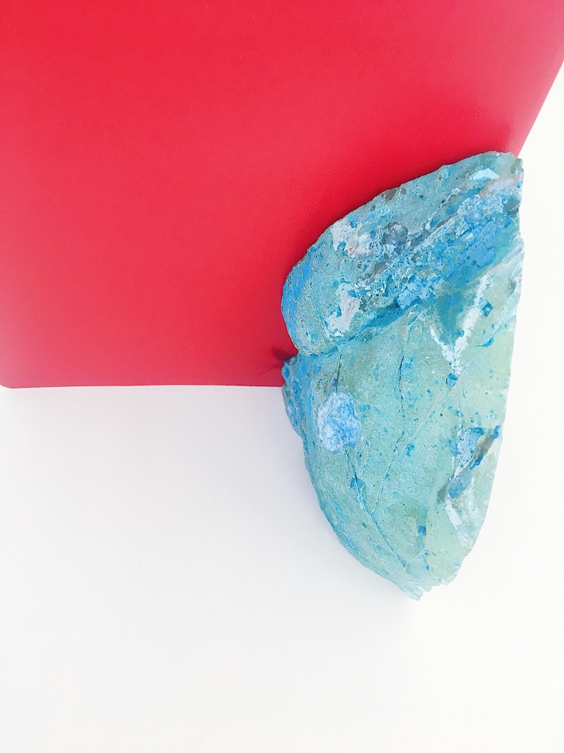 May include: A blue and white textured rock with a red background.