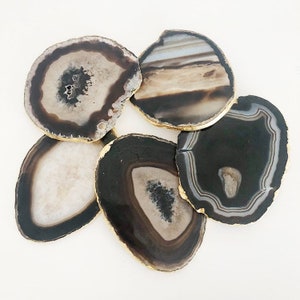 May include: Set of six agate coasters with gold trim. Each coaster features a unique natural pattern of black, white, and brown agate.
