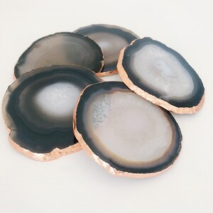May include: Set of six agate coasters with a black and white pattern and a copper-colored rim.