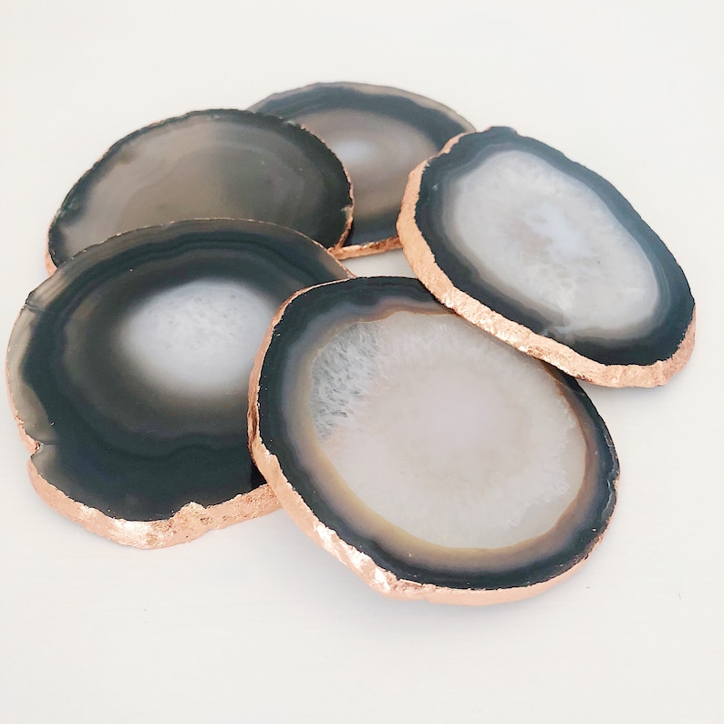May include: Set of six agate coasters with a black and white pattern and a copper-colored rim.