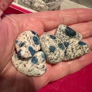 May include: A collection of four blue and white speckled stones. The stones are smooth and have a natural, organic shape.