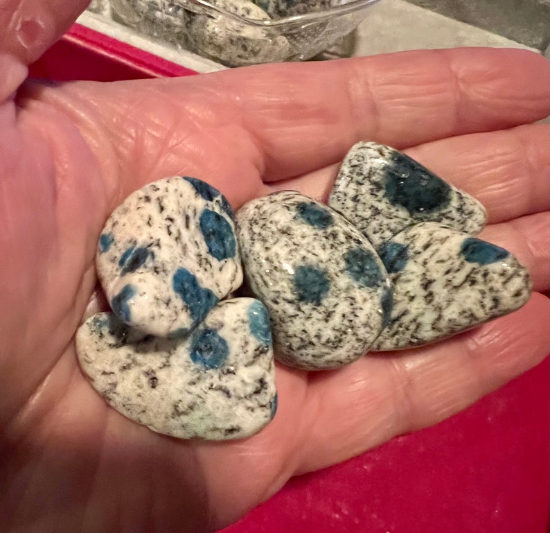 May include: A collection of four blue and white speckled stones. The stones are smooth and have a natural, organic shape.