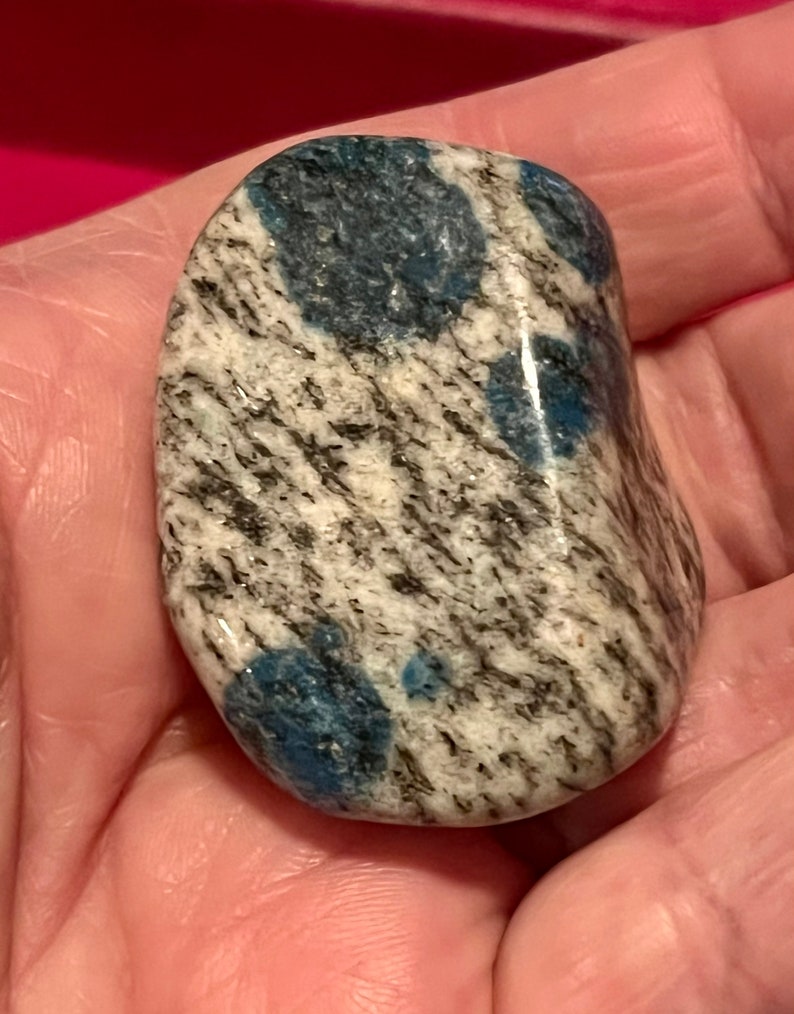 May include: A smooth, polished, gray and white stone with blue, swirling patterns. The stone is a natural, tumbled, polished rock.