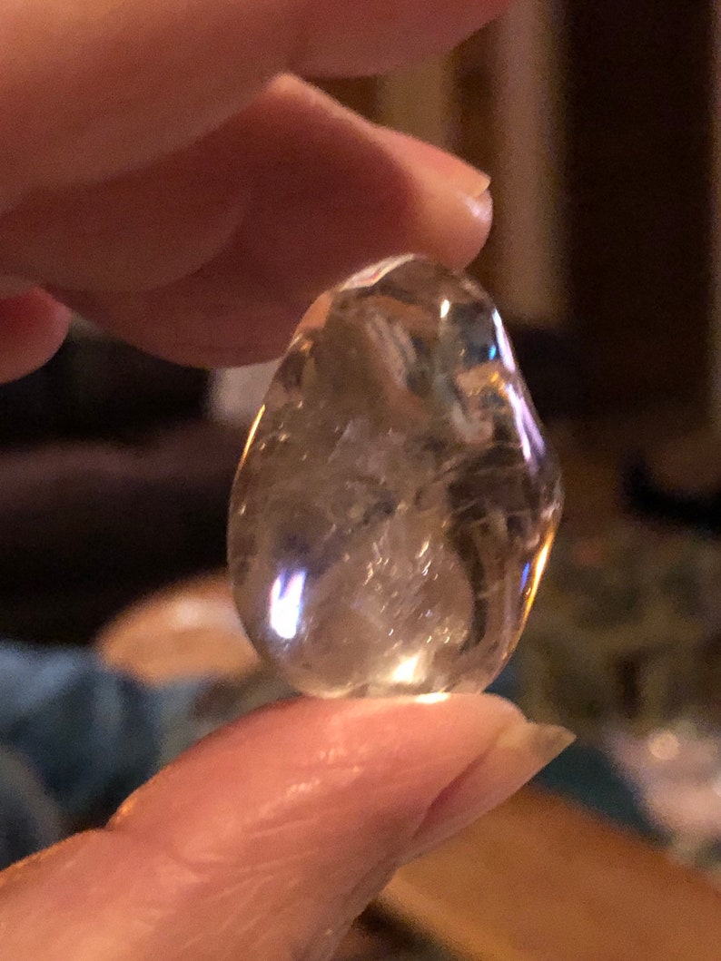 May include: A clear, faceted, teardrop-shaped crystal with a light golden hue.