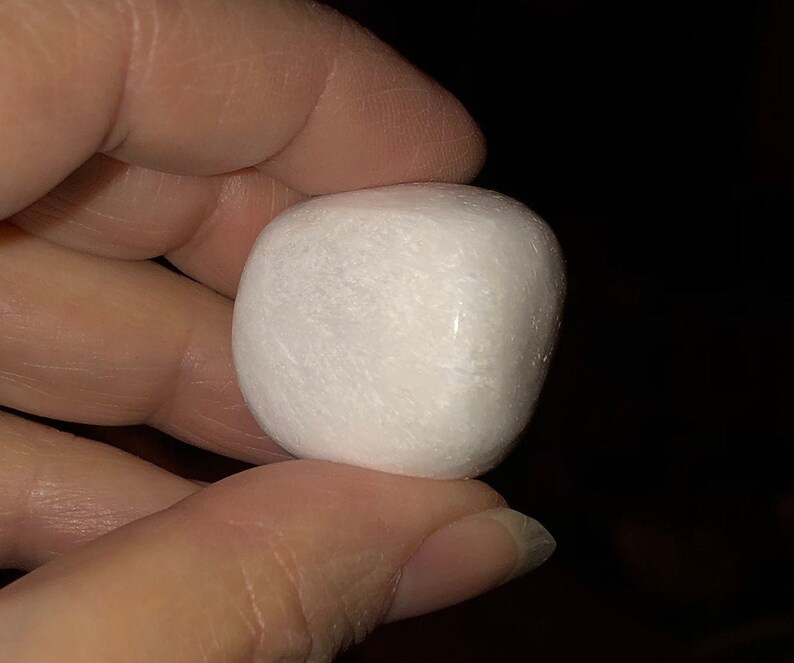 May include: A smooth, white, round stone with a slightly irregular shape.