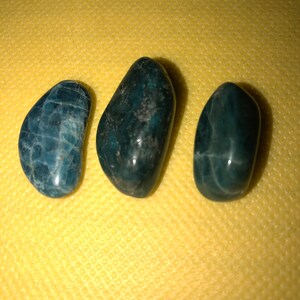 Puede incluir: Tres piedras lisas, de color azul oscuro y verde, con un patr&oacute;n moteado. Las piedras tienen forma ovalada y un acabado brillante.