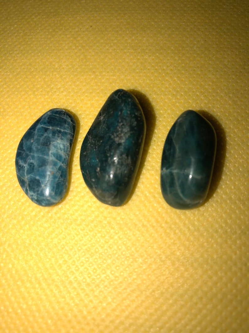 Puede incluir: Tres piedras lisas, de color azul oscuro y verde, con un patr&oacute;n moteado. Las piedras tienen forma ovalada y un acabado brillante.