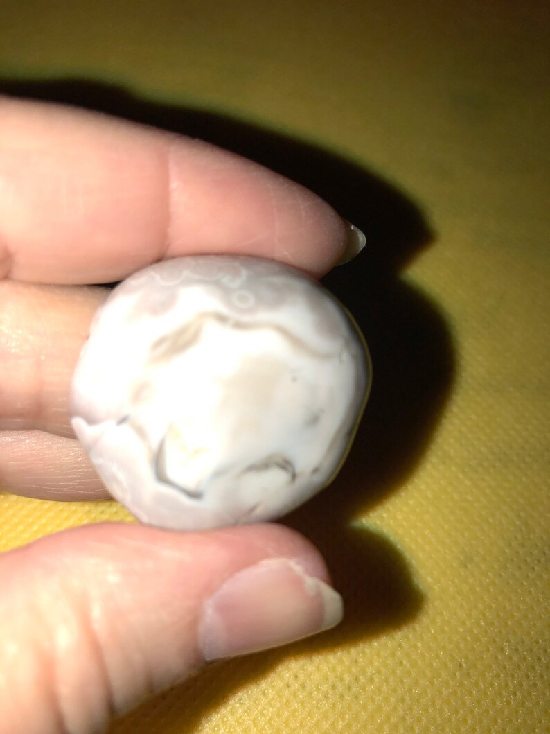 May include: A white agate stone with gray and brown swirls and patterns.