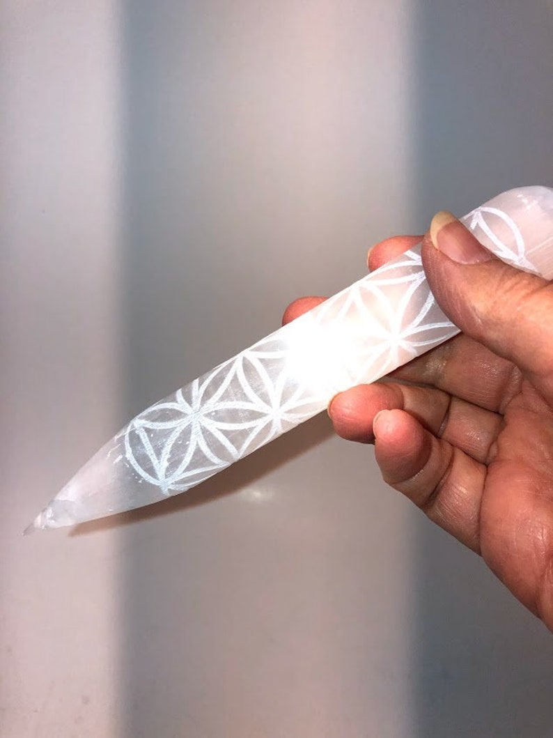 May include: White selenite crystal wand with a carved flower of life design. The wand is approximately 6 inches long.