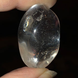 May include: A clear, smooth, oval-shaped crystal. The crystal is translucent and has a slight shimmer.