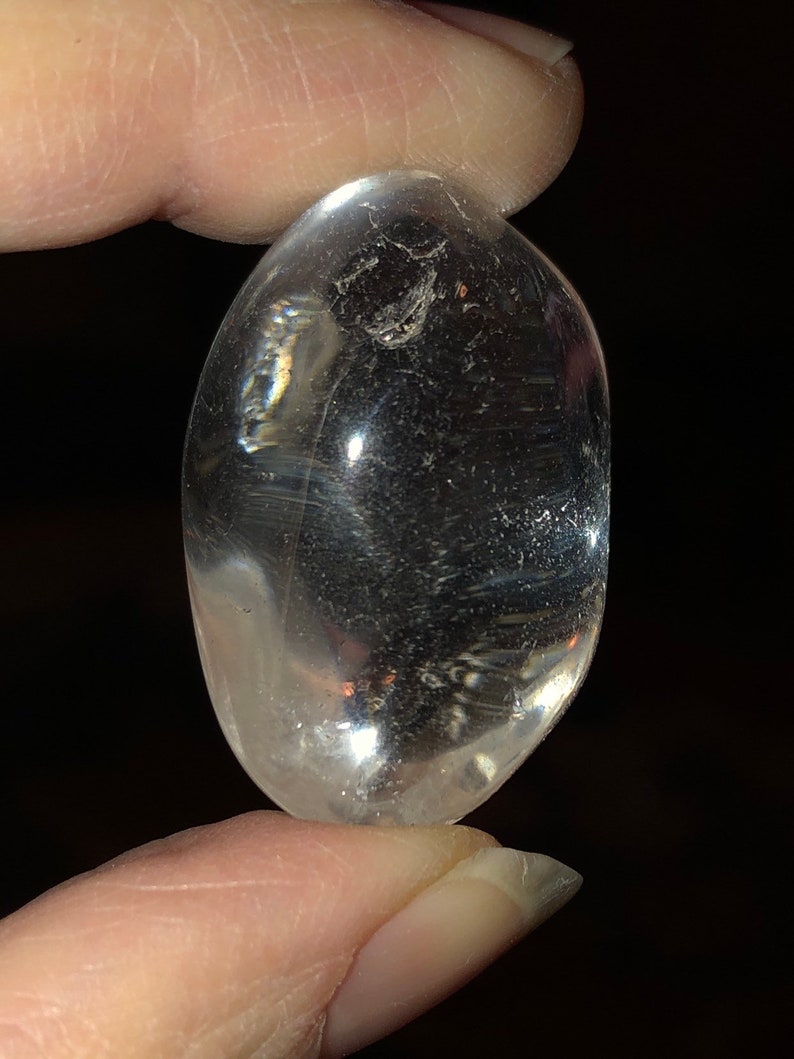 May include: A clear, smooth, oval-shaped crystal. The crystal is translucent and has a slight shimmer.