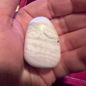 Op de afbeelding: Witte, gladde, ovale steen met witte en grijze strepen.