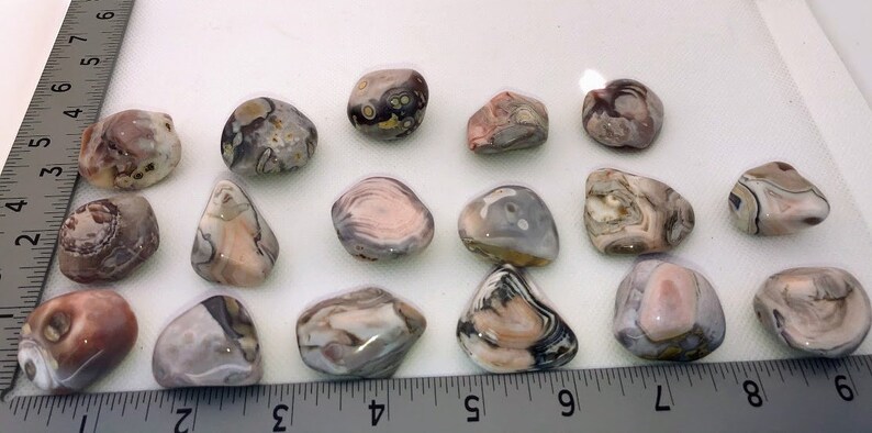 May include: A collection of 15 tumbled agate stones in various shades of pink, brown, and gray with intricate patterns. The stones are smooth and polished, with a natural, organic look.