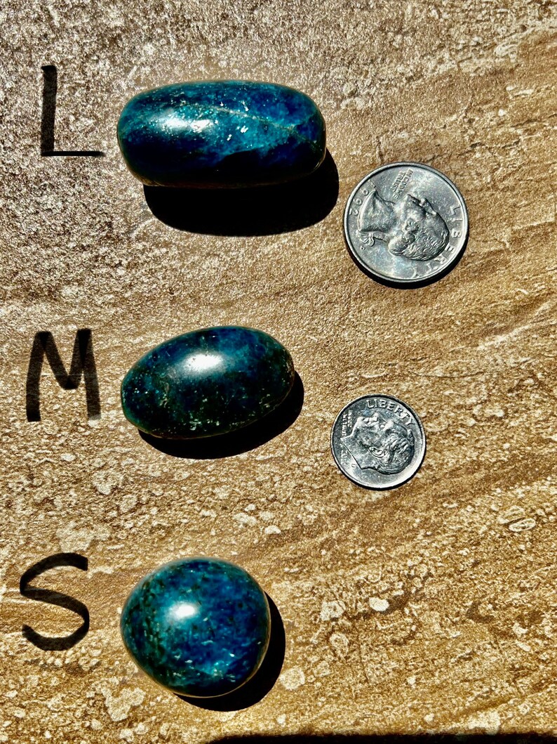 Puede incluir: Tres piedras pulidas de color azul verdoso de diferentes tama&ntilde;os, etiquetadas como "L", "M" y "S" para grande, mediano y peque&ntilde;o. Cada piedra est&aacute; junto a una moneda de 25 centavos de d&oacute;lar estadounidense para comparar el tama&ntilde;o.