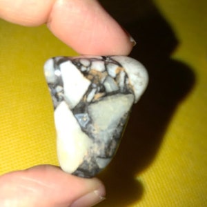 Peut inclure: Gros plan sur une petite pierre mouchet&eacute;e de blanc et de noir, de forme irr&eacute;guli&egrave;re et rugueuse.