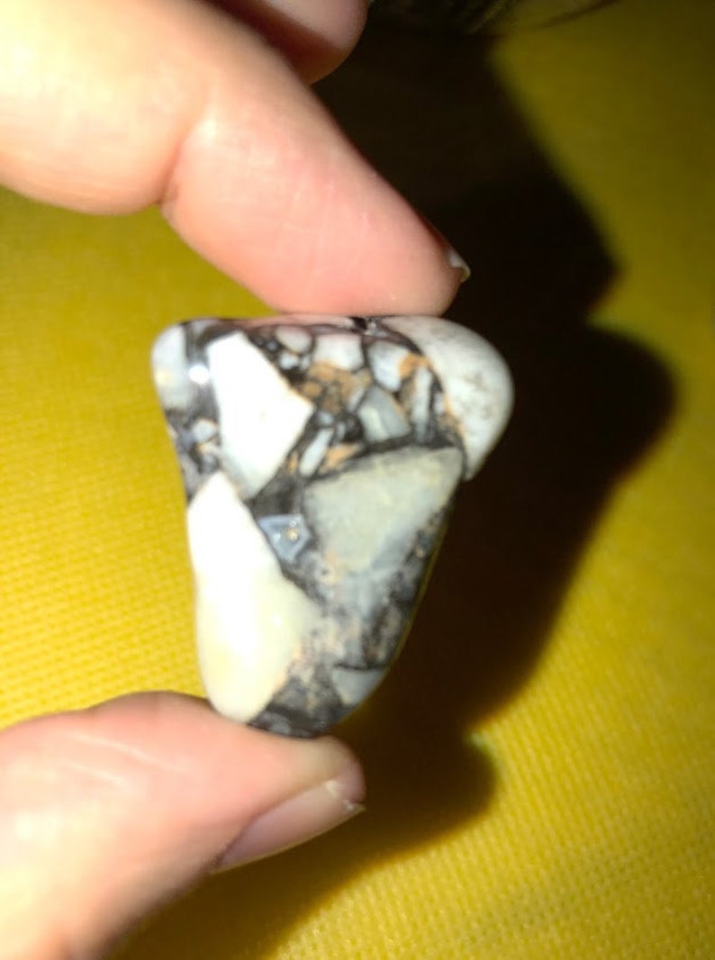 Peut inclure: Gros plan sur une petite pierre mouchet&eacute;e de blanc et de noir, de forme irr&eacute;guli&egrave;re et rugueuse.