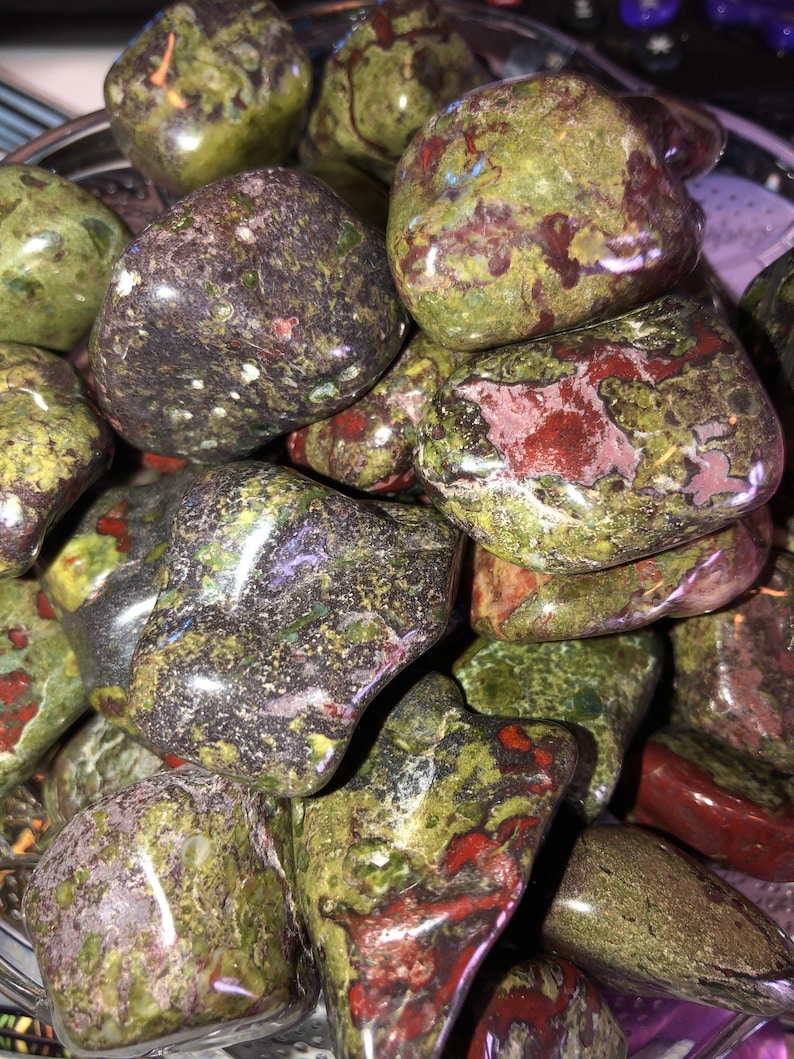 May include: A collection of polished green, red, and black jasper stones. The stones are smooth and have a variety of patterns and textures.