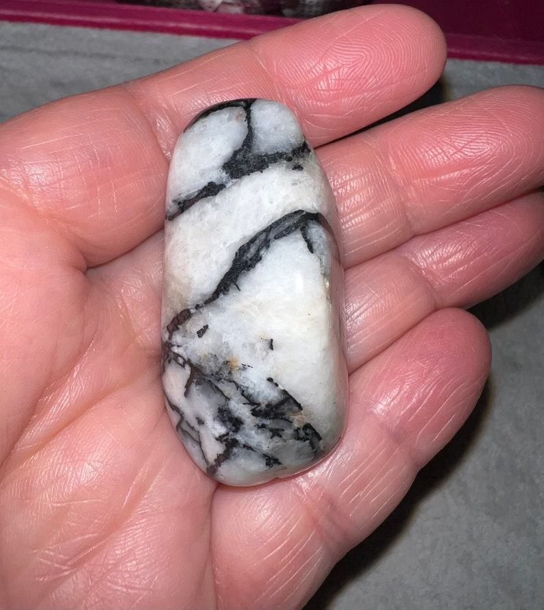 Peut inclure: Une pierre polie de forme ronde et lisse, avec des rayures blanches et noires.