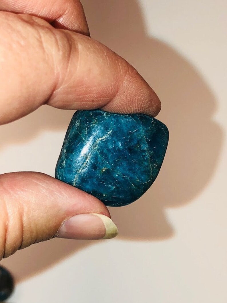 Puede incluir: Una piedra lisa de color azul verdoso oscuro, de forma ligeramente irregular.