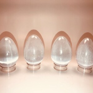Satin Spar Gypsum, aka Selenite, Egg with Acrylic Stand; The egg is approximately 2.5-2.75 inches high by 1 3/4-1 7/8 inches wide.
