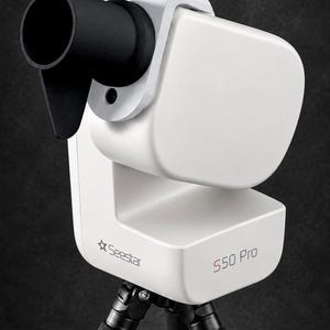 Op de afbeelding: Een witte Seestar S50 Pro slimme telescoop gemonteerd op een zwart statief. Het apparaat heeft een opvallende zwarte cilindrische lensbehuizing bevestigd aan een witte rechthoekige behuizing met de tekst Seestar en S50 Pro op de zijkant.