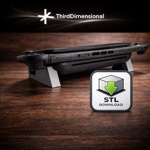 May include: A black handheld gaming device rests on a gray stand. The device has attached controllers and is positioned on a wooden surface. The image includes the text "ThirdDimensional" and an icon with the text "STL DOWNLOAD".