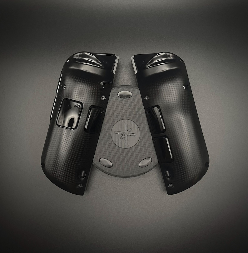 May include: Black gaming controller accessories, featuring a textured surface and a central base with a circular design and a symbol. The controller components are positioned on a dark gray background.