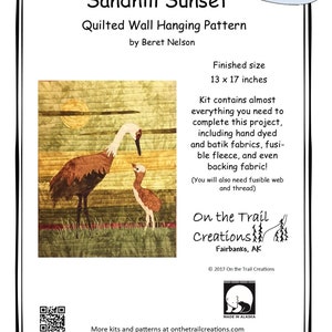 May include: A quilting pattern for a wall hanging featuring a sandhill crane and its chick against a sunset background. The pattern is titled "Sandhill Sunset" and is by Beret Nelson. The pattern is available in kit form. The finished size is 13 x 17 inches.