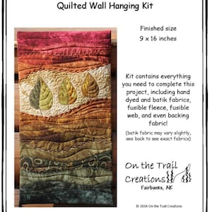 May include: A quilted wall hanging kit featuring autumn leaves in shades of red, orange, yellow, and green. The kit includes hand-dyed and batik fabrics, fusible fleece, fusible web, and backing fabric. The finished size is 9 x 16 inches.  "On the Trail Creations" is printed on the bottom right corner of the image.