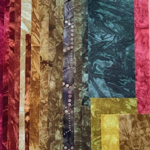 May include: Assortment of fabric strips in various shades of brown, green, and red. The fabric strips are arranged vertically and have a tie-dye pattern.