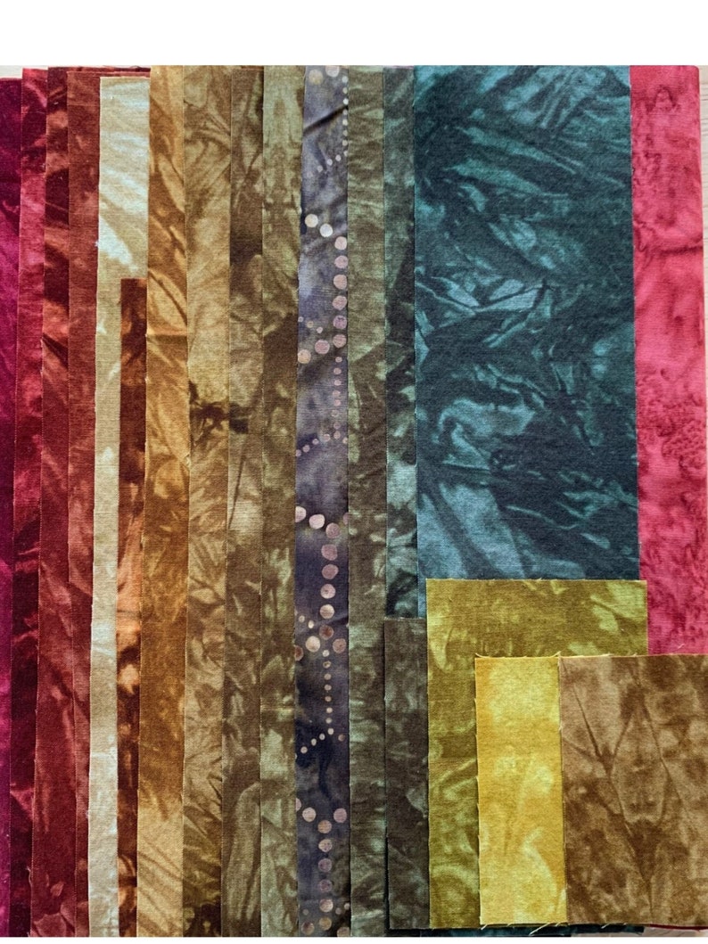 May include: Assortment of fabric strips in various shades of brown, green, and red. The fabric strips are arranged vertically and have a tie-dye pattern.