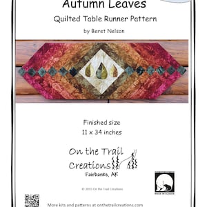 May include: Quilted table runner pattern for sewing, titled "Autumn Leaves" by Beret Nelson. The pattern features a design of autumn leaves in shades of brown, green, and red. The finished size is 11 inches by 34 inches. The pattern is available as a download or in a kit.
