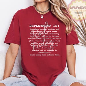 K&ouml;nnte beinhalten: Ein weinrotes T-Shirt mit dem Text "DEPLOYMENT IS:" gefolgt von einem Gedicht &uuml;ber den Einsatz, mit den Worten "Red Friday" in Schreibschrift. Das Shirt hat auch den Text "MAMA4SEVE creations" in der oberen rechten Ecke.