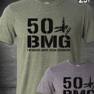 Puede incluir: Dos camisetas con un estampado gráfico negro de "50 BMG" y un diseño de bala. El texto debajo del gráfico dice "Me tomo en serio el distanciamiento social."