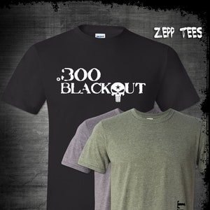 Pode incluir: Três t-shirts em preto, cinza e verde com o texto ".300 BLACKOUT" e um gráfico de caveira. ZEPP TEES está impresso no canto superior direito.
