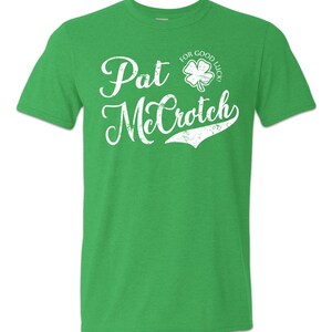 May include: Green t-shirt with a white distressed graphic that says "Pat McCrotich" with a four-leaf clover graphic that says "For Good Luck!"