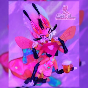May include: A custom doll with a fox-like face, orange and white fur, and large pink wings. The doll is holding a red heart-shaped sign and a mug of beer. The doll is wearing a pink and yellow outfit with black gloves and boots. The doll is a custom creation by Siebel.