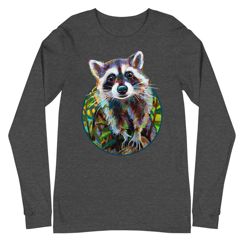 May include: Dark gray long-sleeve shirt featuring a colorful raccoon illustration within a circular frame. The raccoon is depicted with vibrant brushstrokes, showcasing shades of brown, blue, and green. The shirt's sleeves extend to the wrists.
