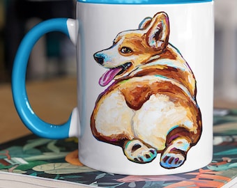 Puede incluir: Taza de café de cerámica blanca con borde azul. La taza presenta una pintura colorida de la parte trasera de un perro corgi.
