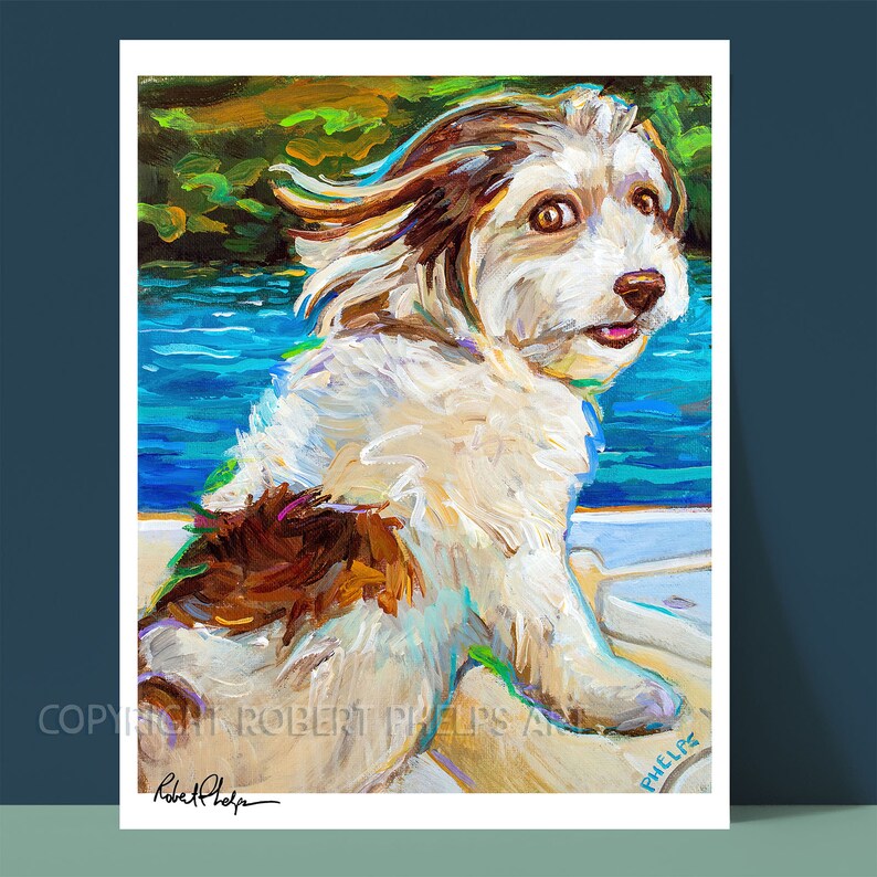 May include: A painting of a white and brown dog with its fur blowing in the wind. The dog is sitting on a boat with blue water in the background. The painting is signed "Robert Phelps" in the bottom left corner and "Phelps" in the bottom right corner.
