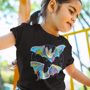 May include: A black t-shirt featuring a colourful graphic of two bats flying in a circle with a starry background.