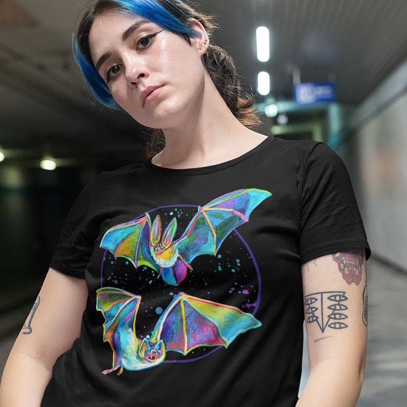 May include: Black t-shirt with a colorful graphic of two bats flying in a circle with a galaxy background.